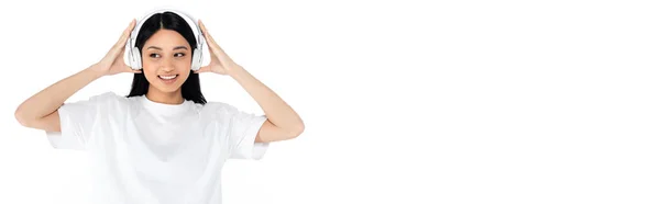 Cheerful Asian Woman Touching Headphones While Listening Music Isolated White — Foto Stock