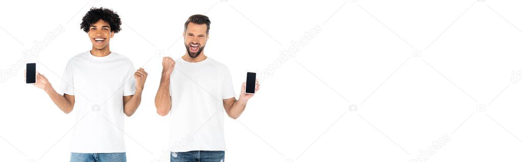 excited interracial men with mobile phones screaming and showing win gesture isolated on white, banner