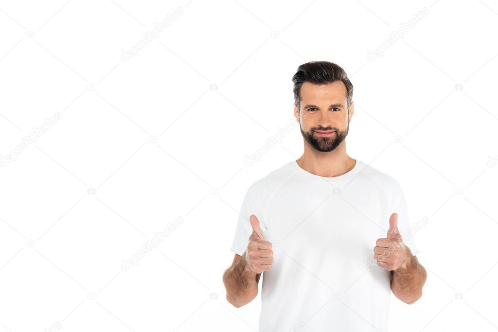 pleased bearded man looking at camera and showing thumbs up isolated on white