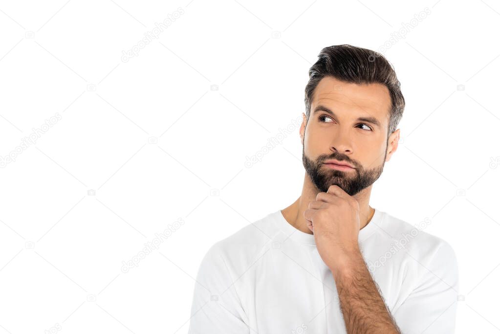 thoughtful man in t-shirt holding hand near chin while looking away isolated on white