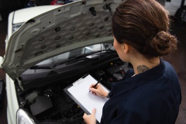 Servis kaputu açık olan arabanın yanındaki panoda yüksek açılı mekanik yazı görünümü 