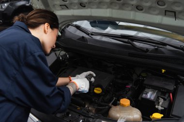 Tamirci garajda araba motoruyla çalışıyor. 