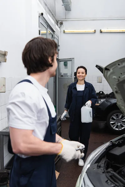 Smiling Mechanic Holding Canister Blurred Colleague Car Service — Stock Photo, Image