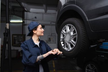 Hizmette otomatiğe yakın pano tutan dövmeli tamircinin yan görünümü 