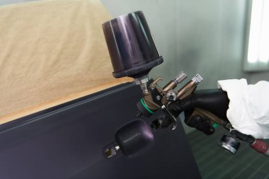 Garajdaki eldiven boyalı araba kapısında çalışan işçiyi gördüm. 