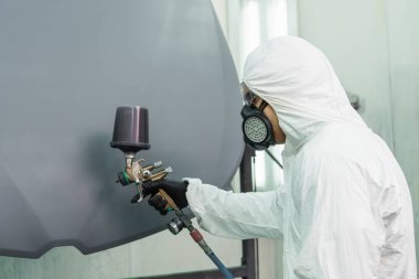 Servis sırasında solunum cihazının kaputunu boyayan işçinin yan görünümü 