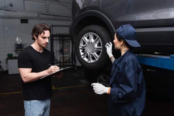 Mechanic Pointing Car Wheel Colleague Writing Clipboard Service — Stock Photo, Image