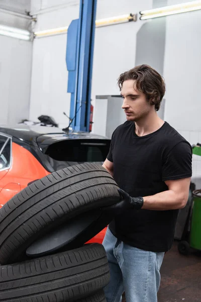 Mladý Dělník Drží Pneumatiky Při Práci Autoservisu — Stock fotografie