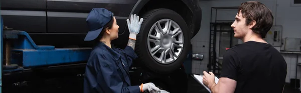 Workwoman Uniforme Apontando Para Auto Perto Colega Com Área Transferência — Fotografia de Stock