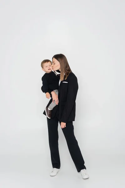 Full Length Mother Holding Arms Kissing Toddler Son Grey — Stockfoto