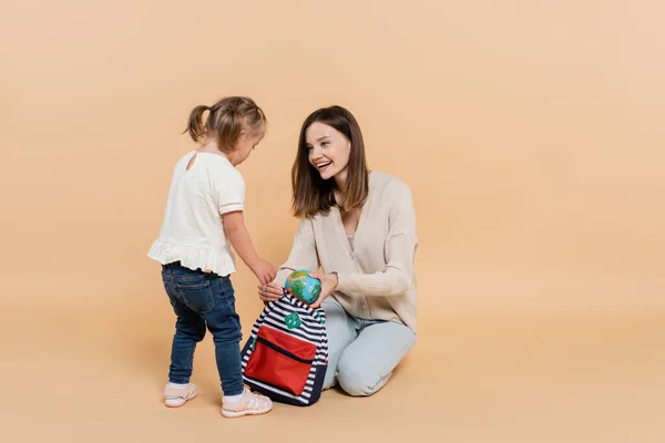 Happy Woman Holding Small Globe Backpack While Looking Kid Syndrome — 图库照片
