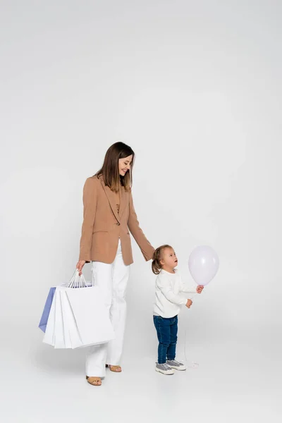 Happy Mother Holding Shopping Bags Looking Girl Syndrome Balloon Grey — Stockfoto