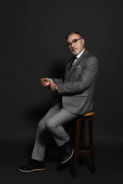 Full Length View Senior Man Suit Eyeglasses Sitting High Stool — стоковое фото