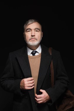 senior bearded man in stylish casual clothes looking at camera isolated on black