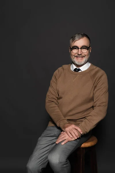 Senior Man Stylish Clothes Eyeglasses Sitting Stool Smiling Camera Dark — стоковое фото