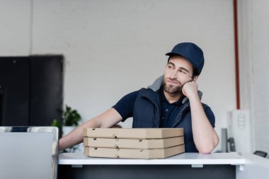 Upset courier standing near pizza boxes on reception in office 