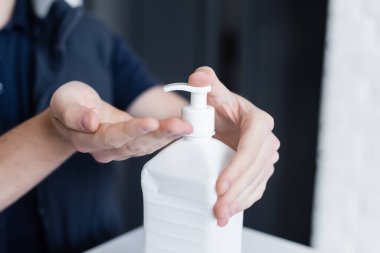 Cropped view of courier applying hand sanitizer in office 
