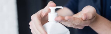 Cropped view of courier applying hand sanitizer, banner 