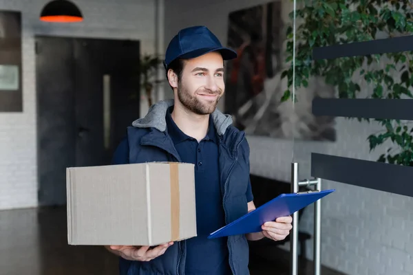 Smiling Courier Uniform Holding Carton Box Clipboard Hallway — Foto de Stock