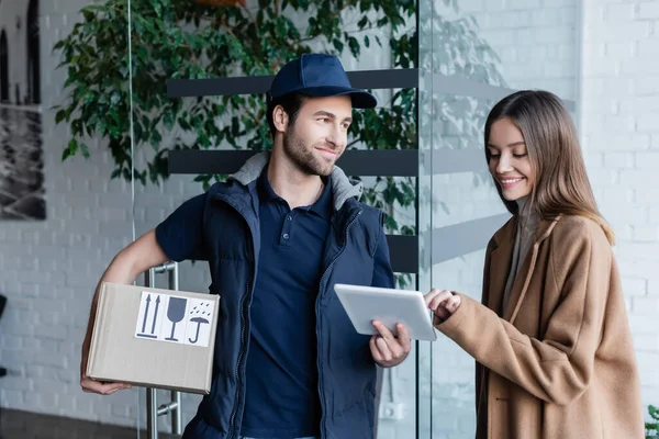 Smiling Woman Using Digital Tablet Courier Cardboard Box Hallway — Stok fotoğraf