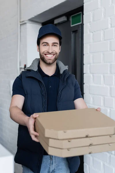 Positive Courier Holding Blurred Pizza Boxes Hallway — стоковое фото