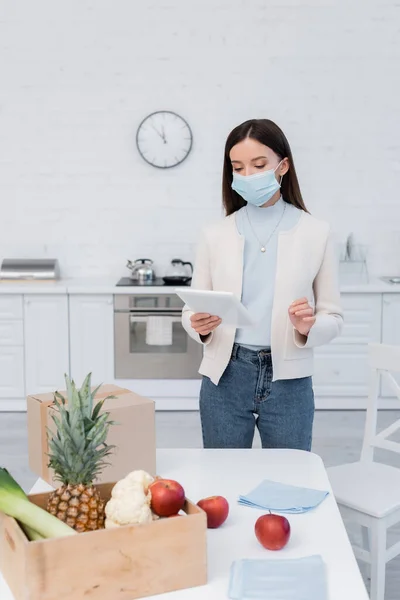 Woman Medical Mask Holding Digital Tablet Fresh Food Carton Box — Stock Fotó