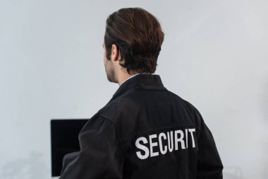 back view of guard in black uniform with security lettering in office clipart