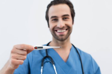 Bulanık arkaplanda gülümseyen elektronik termometresi olan bulanık doktor gri üzerine izole edilmiş.