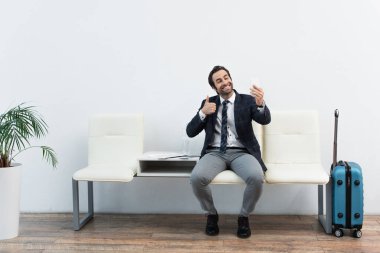 Keyifli bir adam hareket salonunda akıllı telefondan selfie çekerken baş parmağını gösteriyor.
