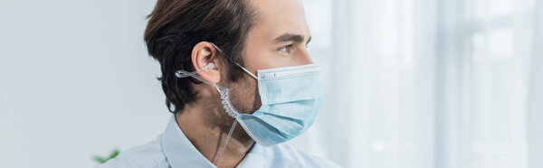 охранник в медицинской маске и наушниках, смотрящий в сторону офиса, баннер