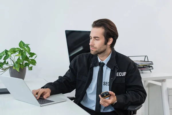 Homem Segurança Uniforme Preto Segurando Walkie Talkie Digitando Laptop — Fotografia de Stock