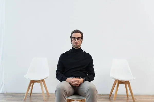 Jovem Elegante Homem Gola Alta Preta Óculos Sentados Cadeira Olhando — Fotografia de Stock