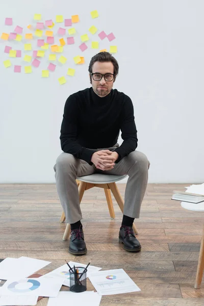 Stylish Man Looking Camera While Sitting Chair Papers Floor — Stock Photo, Image