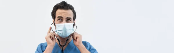 Tıbbi Maskeli Düşünceli Bir Doktor Steteskop Kullanıyor Gri Pankartta Izole — Stok fotoğraf