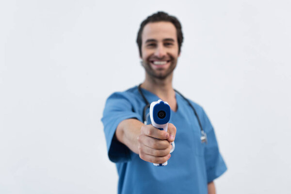 blurred doctor smiling while holding pyrometer isolated on grey