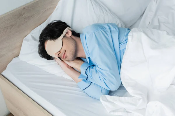 Νεαρός Άνδρας Μάσκα Ύπνου Και Πιτζάμες Κοιμάται Λευκό Κρεβάτι — Φωτογραφία Αρχείου