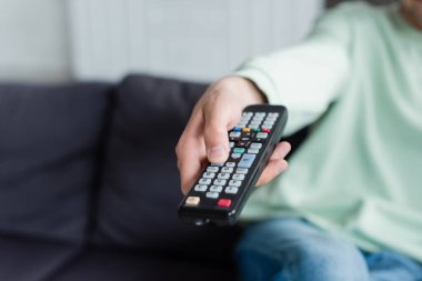 Uzaktan kumandada TV kanallarına tıklayan bulanık adamın görüntüsü