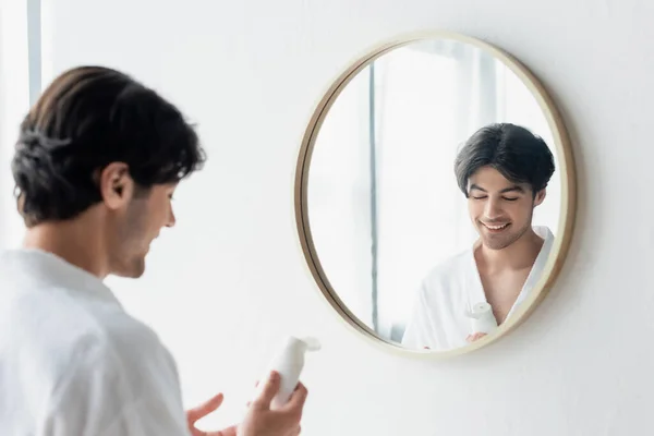 Hombre Sonriente Albornoz Blanco Sosteniendo Crema Manos Cerca Del Espejo — Foto de Stock