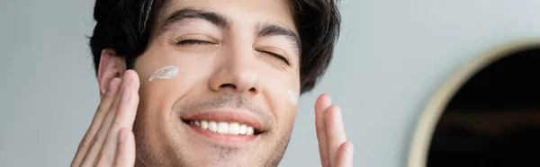 Close View Smiling Man Closed Eyes Applying Face Cream Banner — Stock Photo, Image
