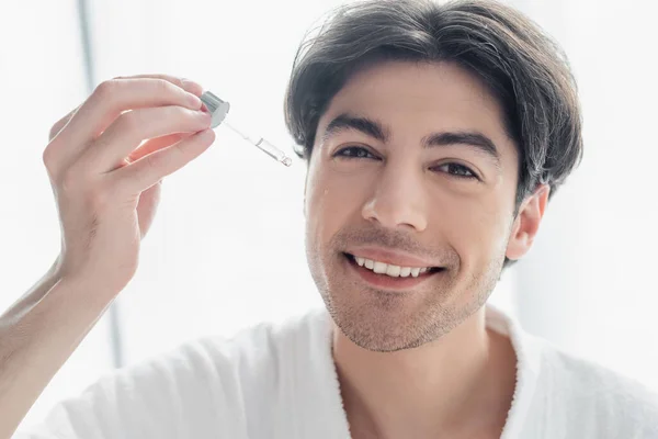 Homem Feliz Olhando Para Câmera Aplicar Soro Cosmético Banheiro — Fotografia de Stock