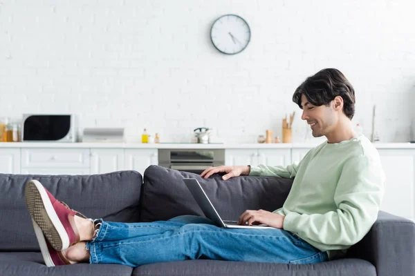 Oversikt Smilende Mann Som Sitter Sofaen Med Laptop Hjemme – stockfoto