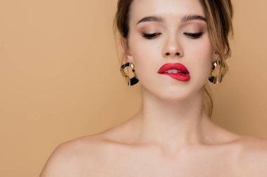 Makyajlı, çıplak omuzlu, dudak ısıran, bej renkli, şehvetli bir kadın.