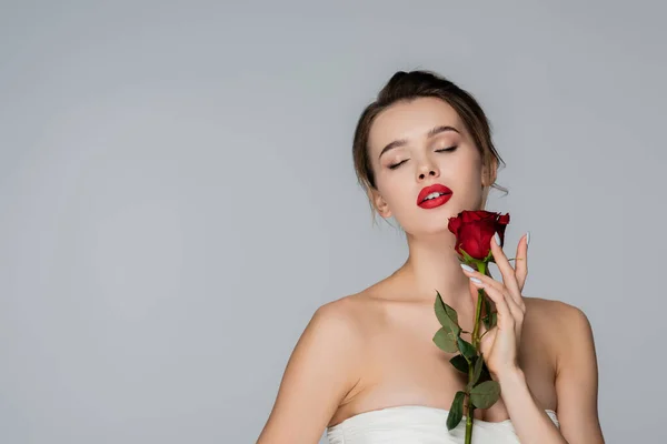 官能的な女性閉じた目と赤いバラを保持裸の肩は灰色で隔離 — ストック写真