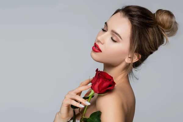 年轻而漂亮的女人 紧闭的眼睛紧盯着红色的玫瑰 近于裸露的肩部 灰色孤立 — 图库照片
