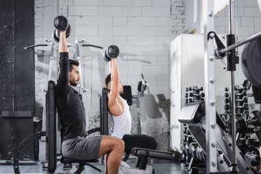 Spor merkezinde dambılları kaldıran ırklar arası sporcuların yan görünüşü 