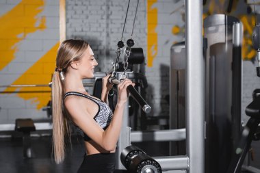 Spor merkezinde dambılı spor yapan genç bir sporcunun yan görüntüsü 