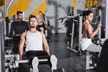 Orta Doğu sporcusu ve spor aletleri yakınında bacak kıvırma makinesinde spor eğitimi 