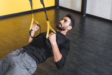Sakallı Müslüman sporcu eğitimi, jimnastik salonunda askılar. 