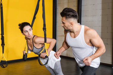 Orta Doğulu kadın spor salonunda jimnastik hocasının yanında askılarla antrenman yapıyor. 