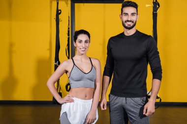 Gülümseyen Arap sporcu spor salonundaki orta doğu sporcusunun yanındaki kameraya bakıyor. 